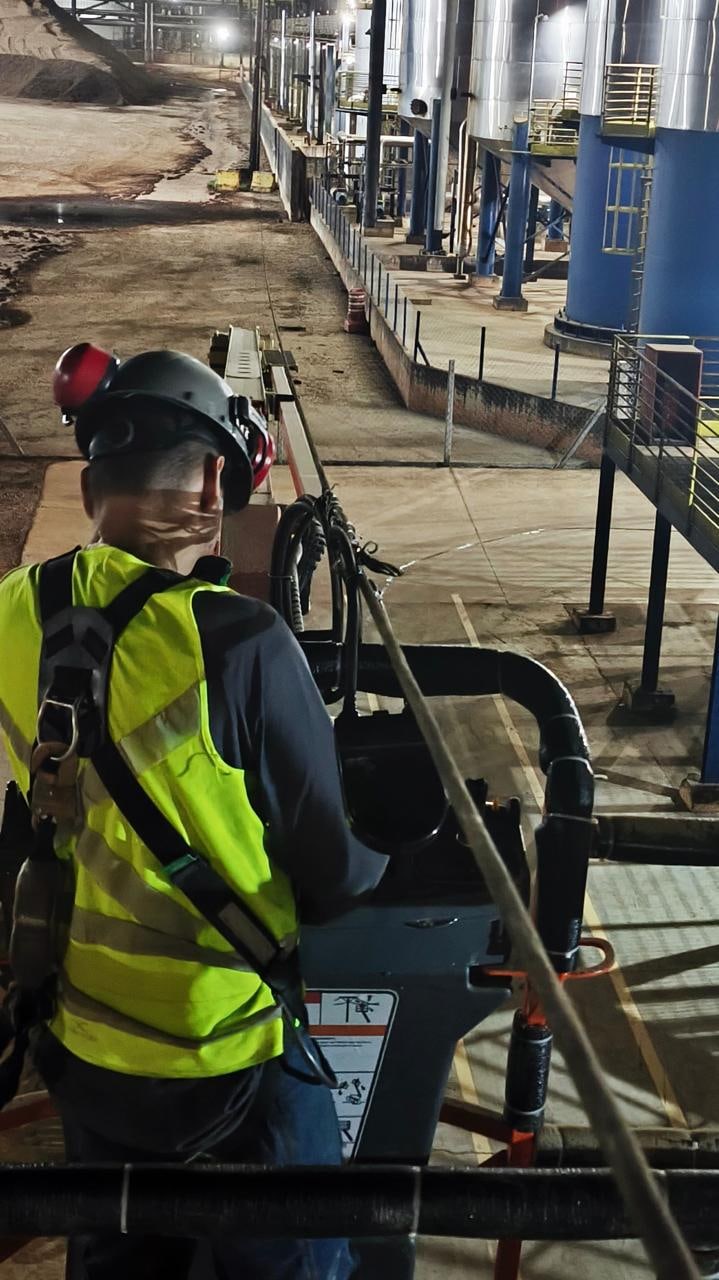 Profissional utilizando capacete e colete de proteção em uma plataforma de trabalho industrial