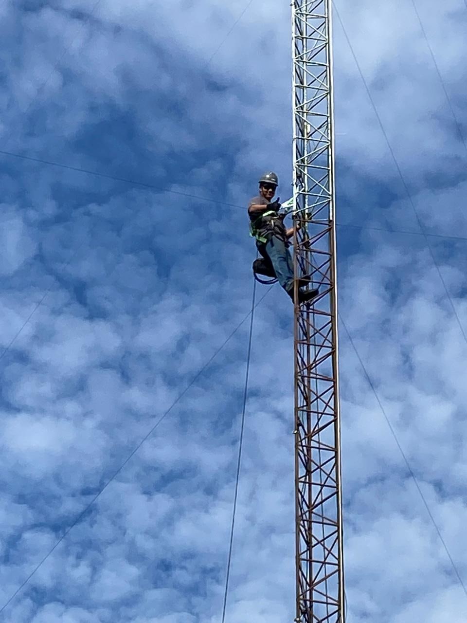 Técnico em uma torre de telecomunicações utilizando equipamentos de proteção