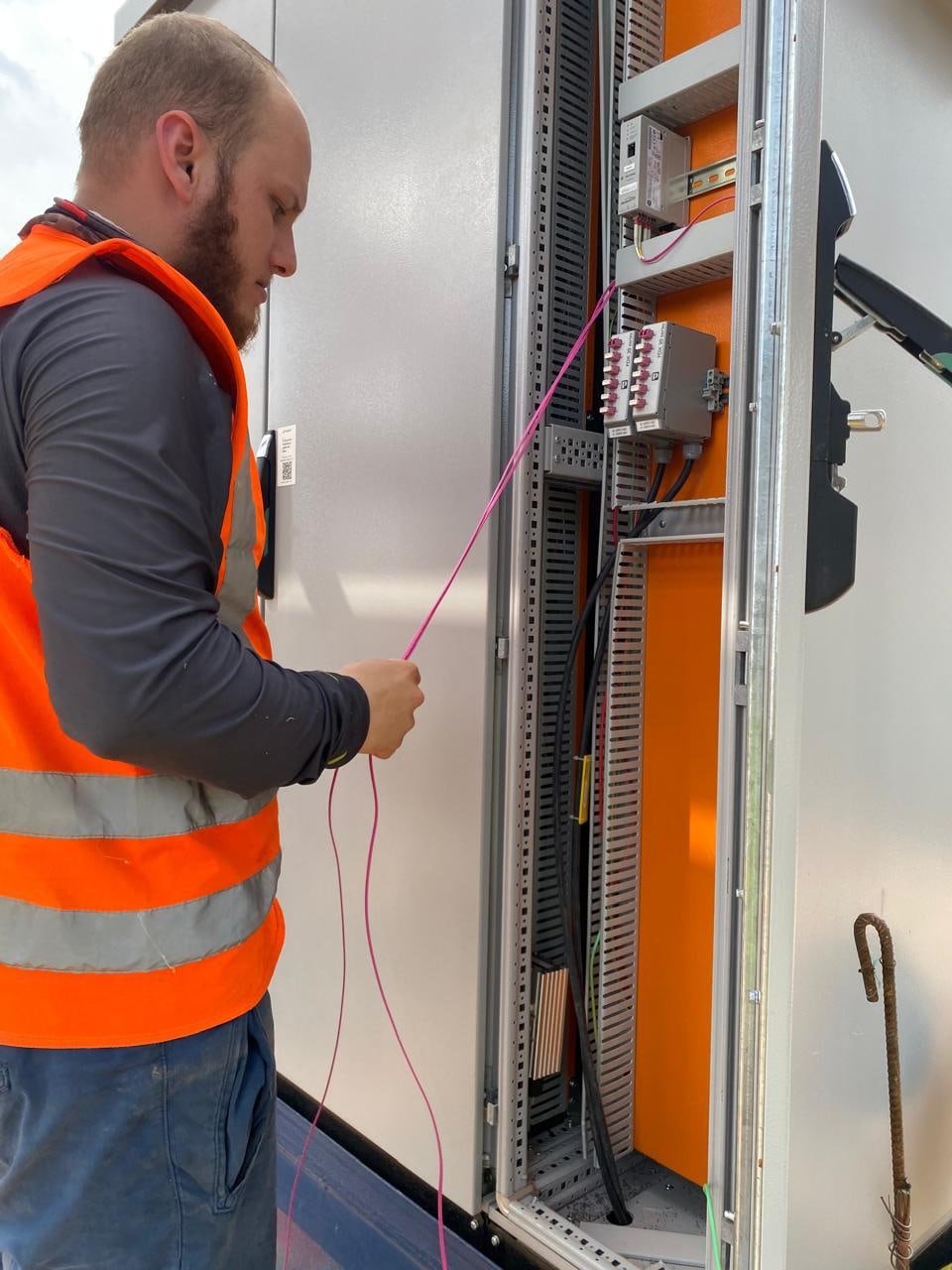 Técnico da Optus trabalhando nas conexões ópticas de um rack